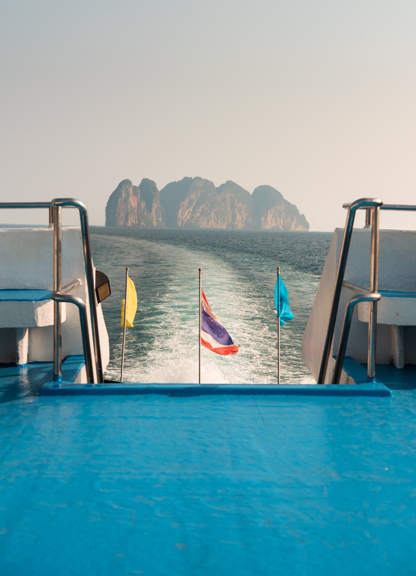A boat navigating through turquoise waters, with the picturesque landscape of Phi Phi Island in the distance.