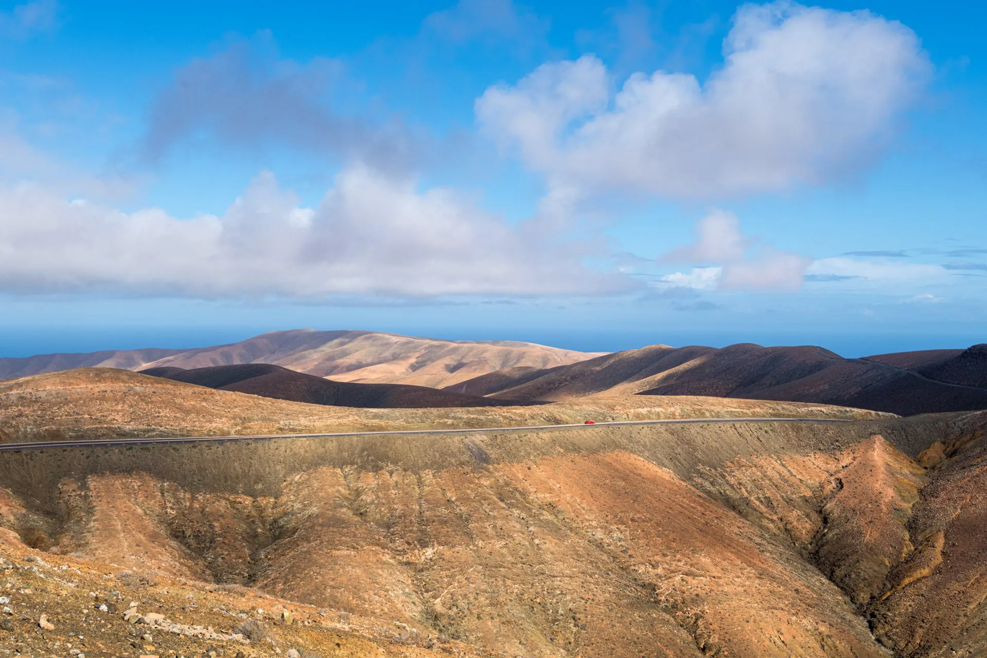 Panoramic landscape view from a hilltop mirador in Fuerteventura with rolling volcanic hills and dramatic cloud formations