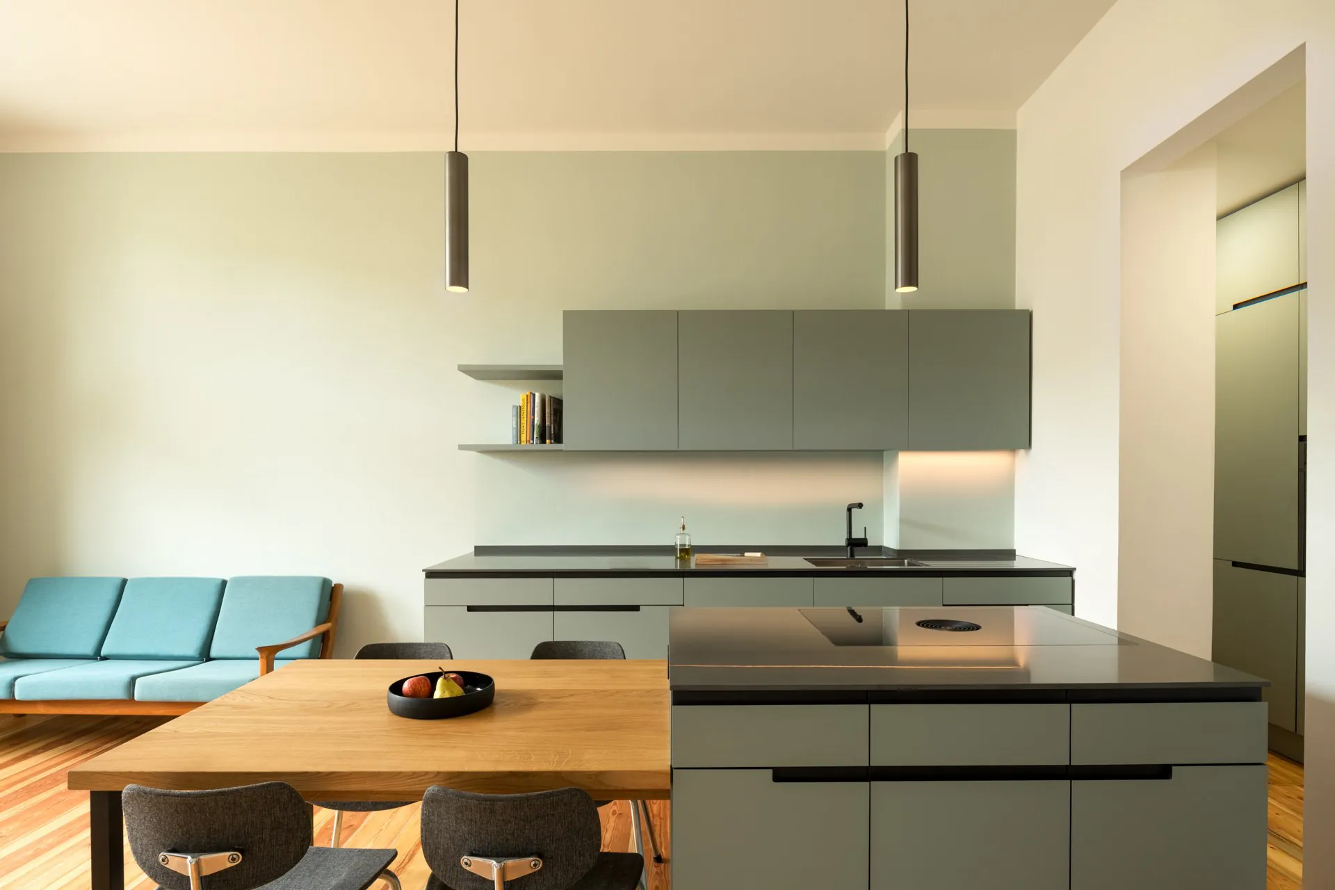 Bright open-plan kitchen and dining area with light timber cabinetry, pendant lighting, and a long central island